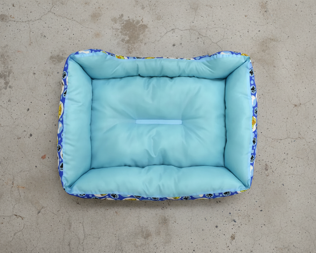 Cama para perro mediana acolchada azul con superficie suave y detalles decorativos.