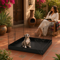 Corral plegable de metal para perro en jardín, perro dentro del corral y mujer leyendo junto a plantas.