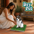 Femme utilisant un tapete de pasto sintético para perro Dry Pet avec un chiot sur la surface verte.