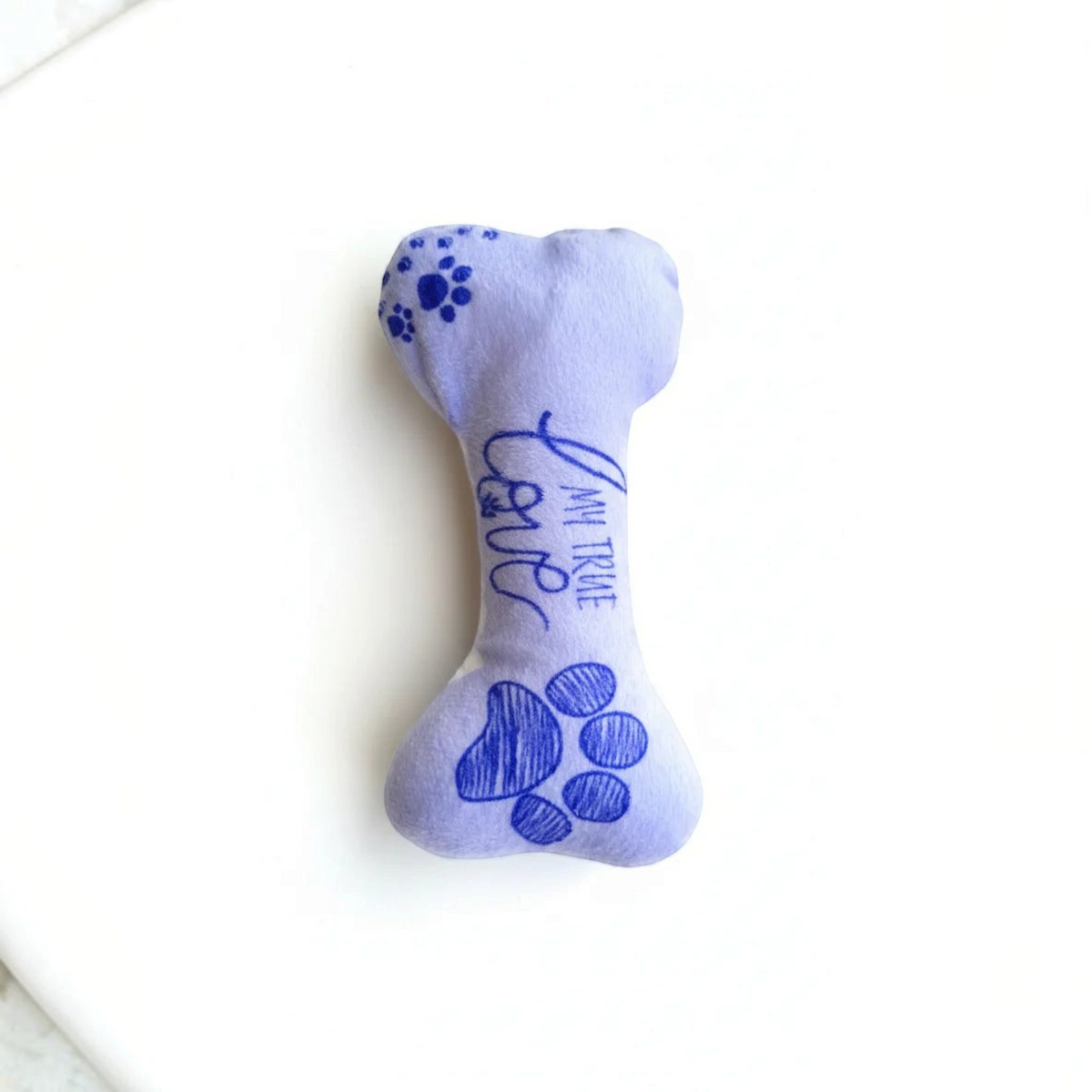 juguete de peluche en forma de hueso para perro Mitzon en color morado con diseño de patas y texto 'I am your true love'.