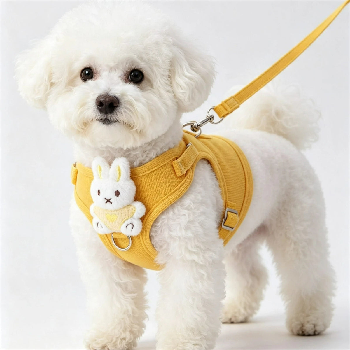 Un perro pequeño con arnés ajustable de malla para perro pequeño de color amarillo y un accesorio de conejito.