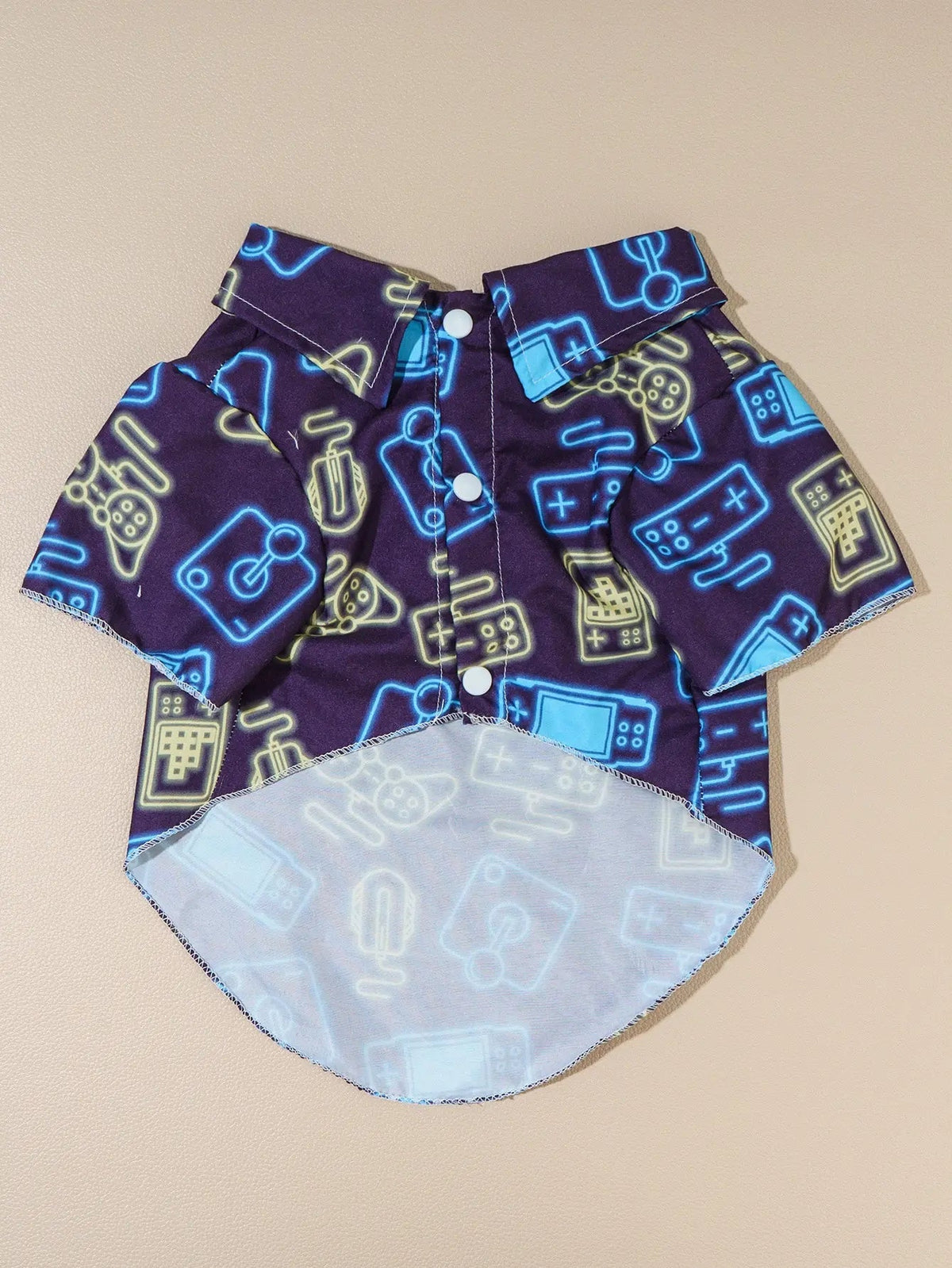 Camisa gamer para perro con estampado de controles en tonos neón azul y amarillo sobre fondo morado.