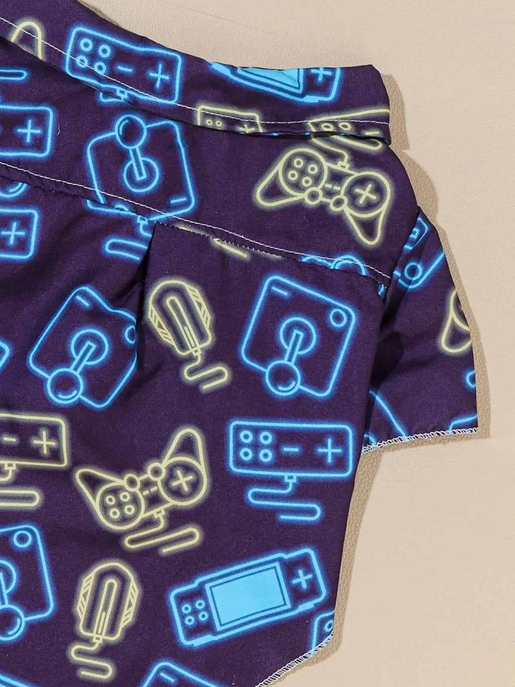 Camisa gamer para perro con estampado de controles en tonos neón azul sobre fondo morado.