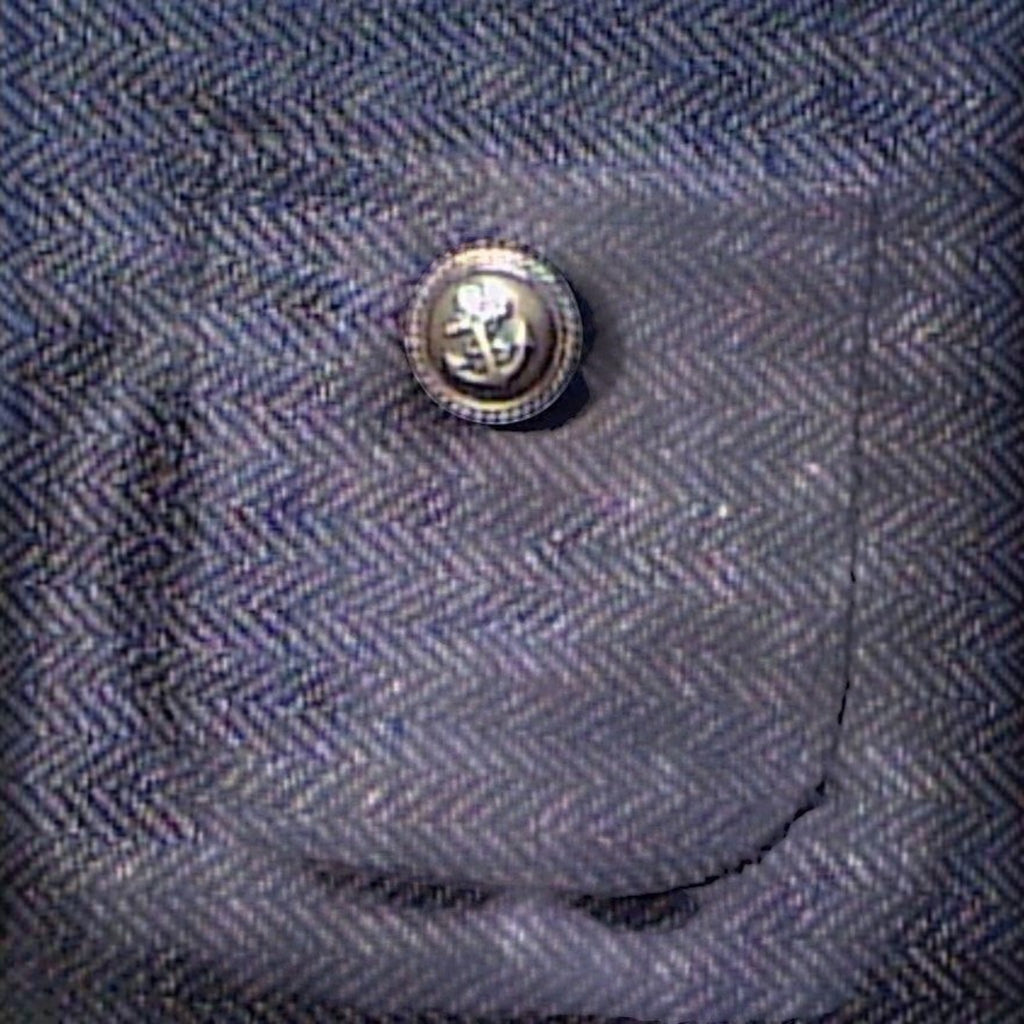 Gros plan sur le motif à chevrons marron du manteau pour chien MITZON avec une poche ornée d'un bouton blazer
