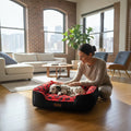 Femme caressant un chiot dalmatien dans un panier MITZON noir et rouge à motifs de pattes dans un salon lumineux.